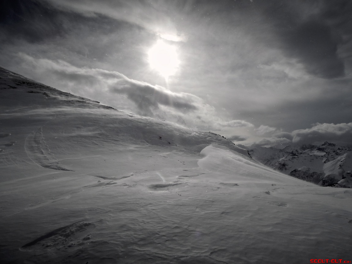 Schwarzweissbild einer verschneiten Berglandschaft im Gegenlicht