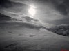 Schwarzweissbild einer verschneiten Berglandschaft im Gegenlicht