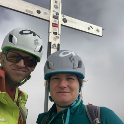 Selfie zweier Kletterer mit Helm am Gipfelkreuz, Jahresrückblick 2021