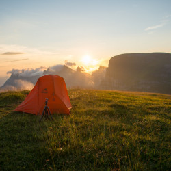 Oranges Zelt auf einer Wiese im Sonnenuntergang, Biwak am Chäserrugg
