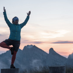 Yoga-Pose auf einem Pfosten vor Bergen in der Dämmerung, Biwak am Chäserrugg