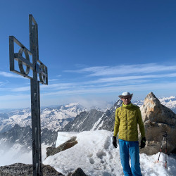 Wanderer am Gipfelkreuz vor verschneiten Gipfeln, Jahresrückblick 2024