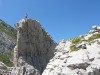 Person auf einem Felsturm unter blauem Himmel