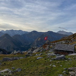 Steinhütte mit Schweizer Fahne auf einer Alp, Via Alta Crio zweiter Teil