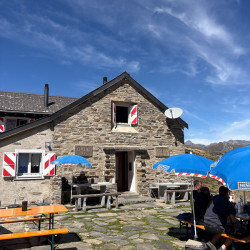 Berghütte mit Sonnenschirmen und Gästen, Via Alta Crio