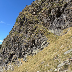 Steile Grasflanke unter einer Felswand, Via Alta Crio