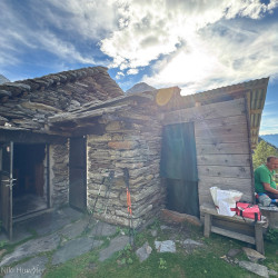 Alte Steinhütte mit Rucksäcken auf einer Alp, Via Alta Crio
