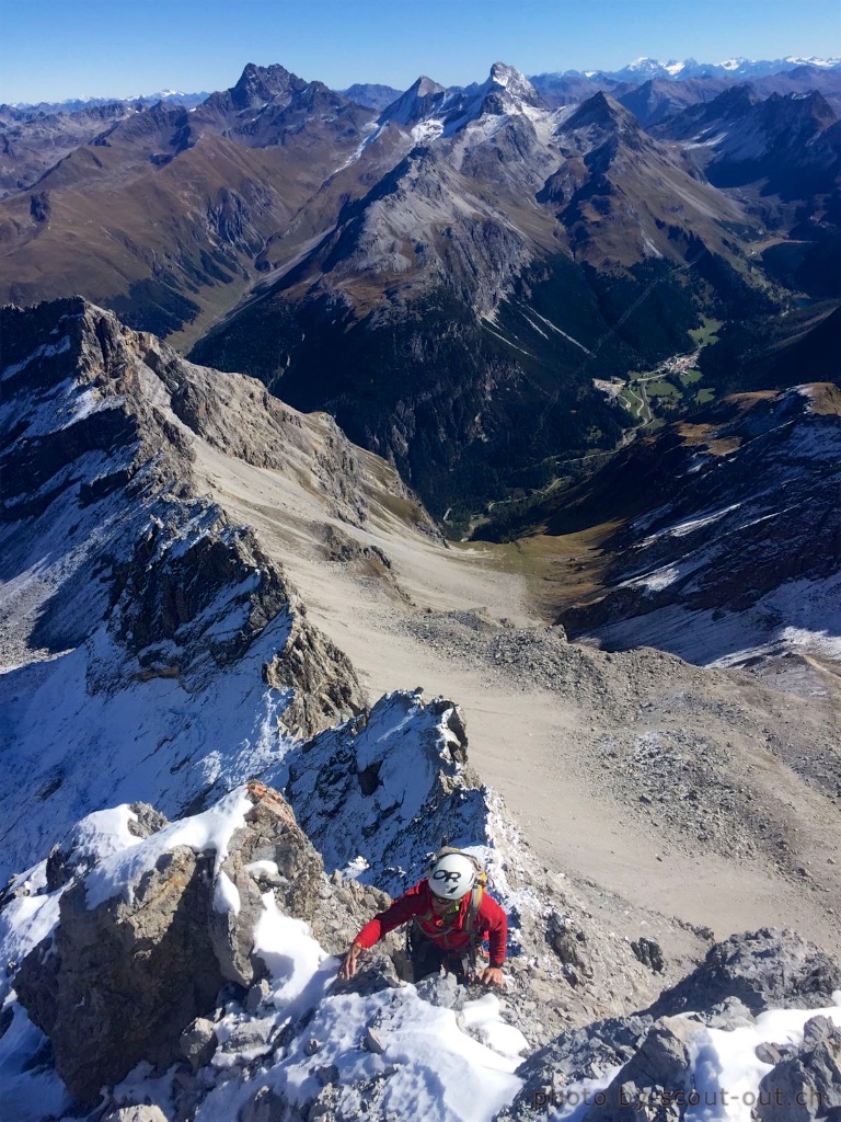 Bergsteiger auf einem verschneiten Grat hoch über einem Tal