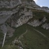 Bergweg in grüner Flanke unter Felswänden, Alpstein