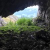 Blick aus einer Höhle auf eine grüne Wiese, Fluebrig