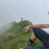 Rastender Wanderer auf einem Grasgrat im Nebel, Fluebrig