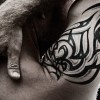 Tribal-Tattoo auf einer Schulter mit Hand