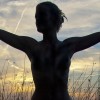 Silhouette einer Person mit ausgebreiteten Armen im Gegenlicht