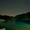 Nacht der Perseiden: Grünlich beleuchteter Bergsee bei Nacht