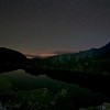Nacht der Perseiden: Bergsee mit Restlicht am Horizont und Sternen
