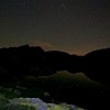 Nacht der Perseiden: Sternenhimmel über einem Bergsee mit Felsen