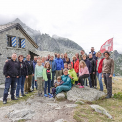 Gruppenfoto vor einer Berghütte mit Schweizer Fahne, Sommer 2020
