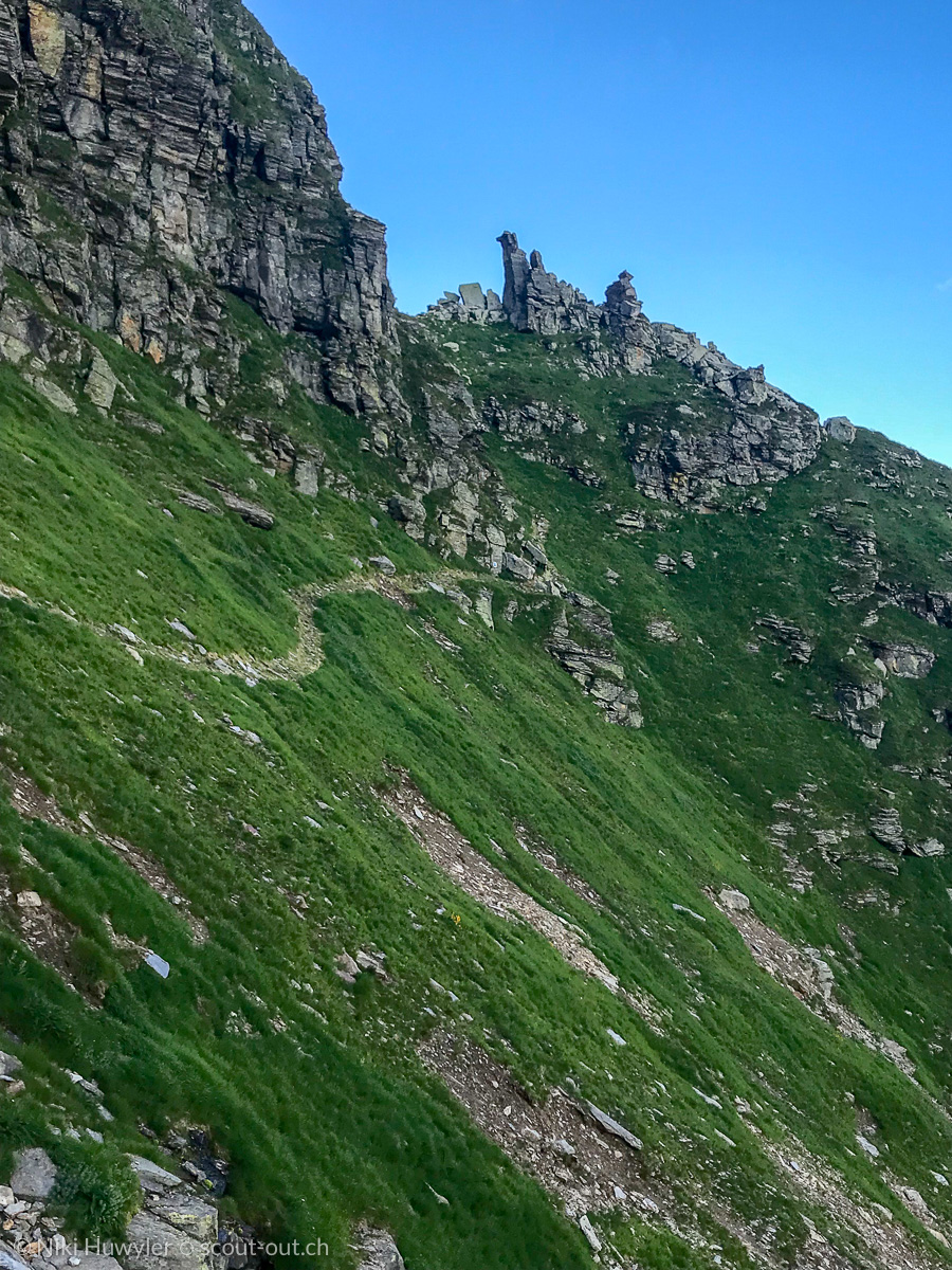 Bergweg in einer steilen Grasflanke unter Felstürmen, Via Alta della Verzasca