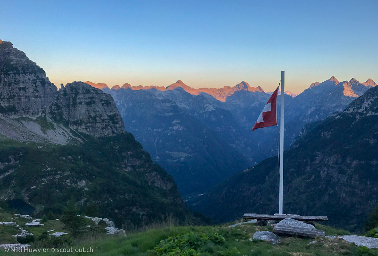 Schweizer Fahne vor Tessiner Bergen in der Morgendämmerung, Via Alta della Verzasca
