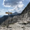 Wegweiser auf einem Geröllpfad unter Felswänden, Via Alta della Verzasca